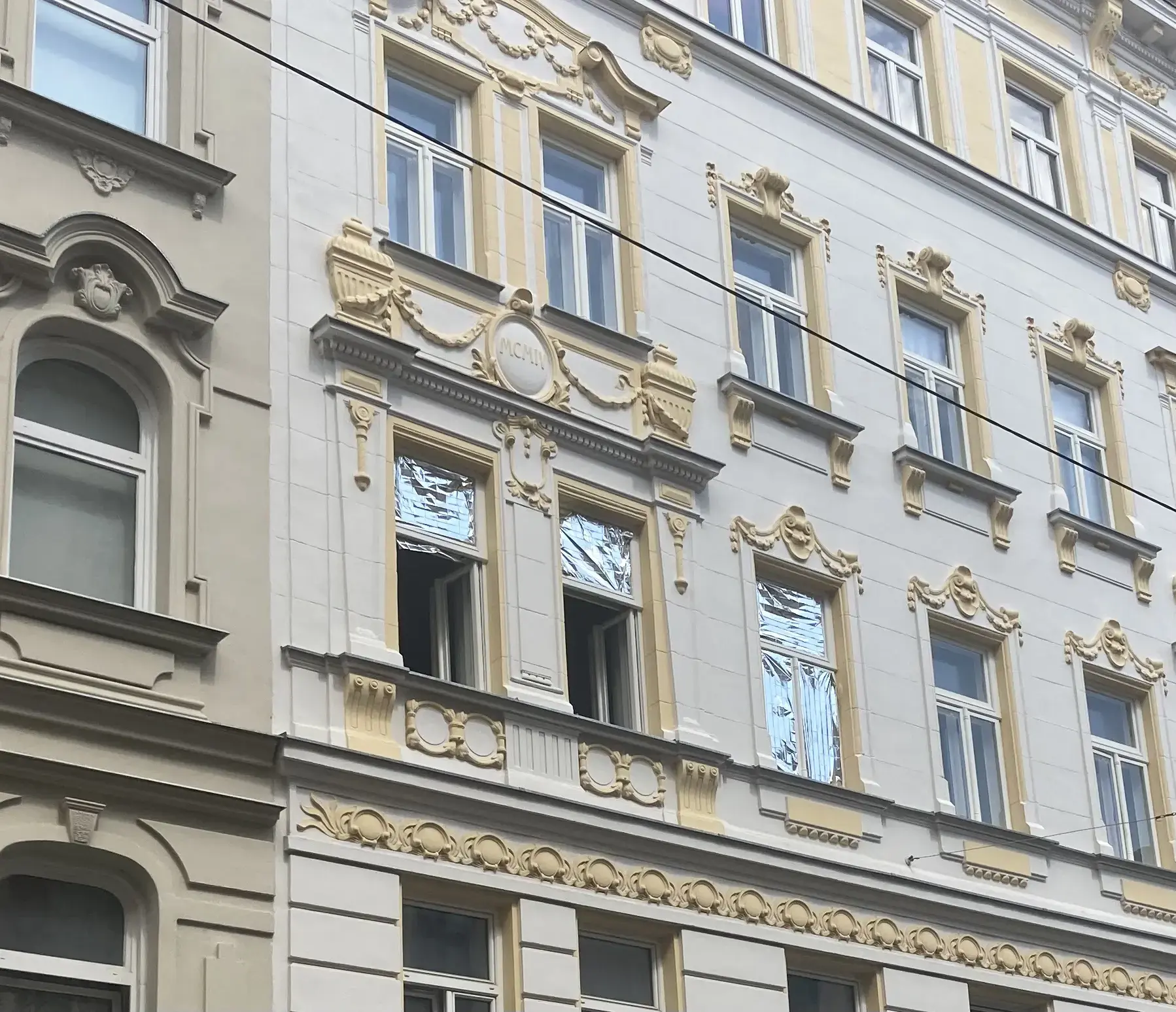 Farbfoto: Stuckfassade mit Fenstern, teilweise mit Rettungsdecke abgedeckt